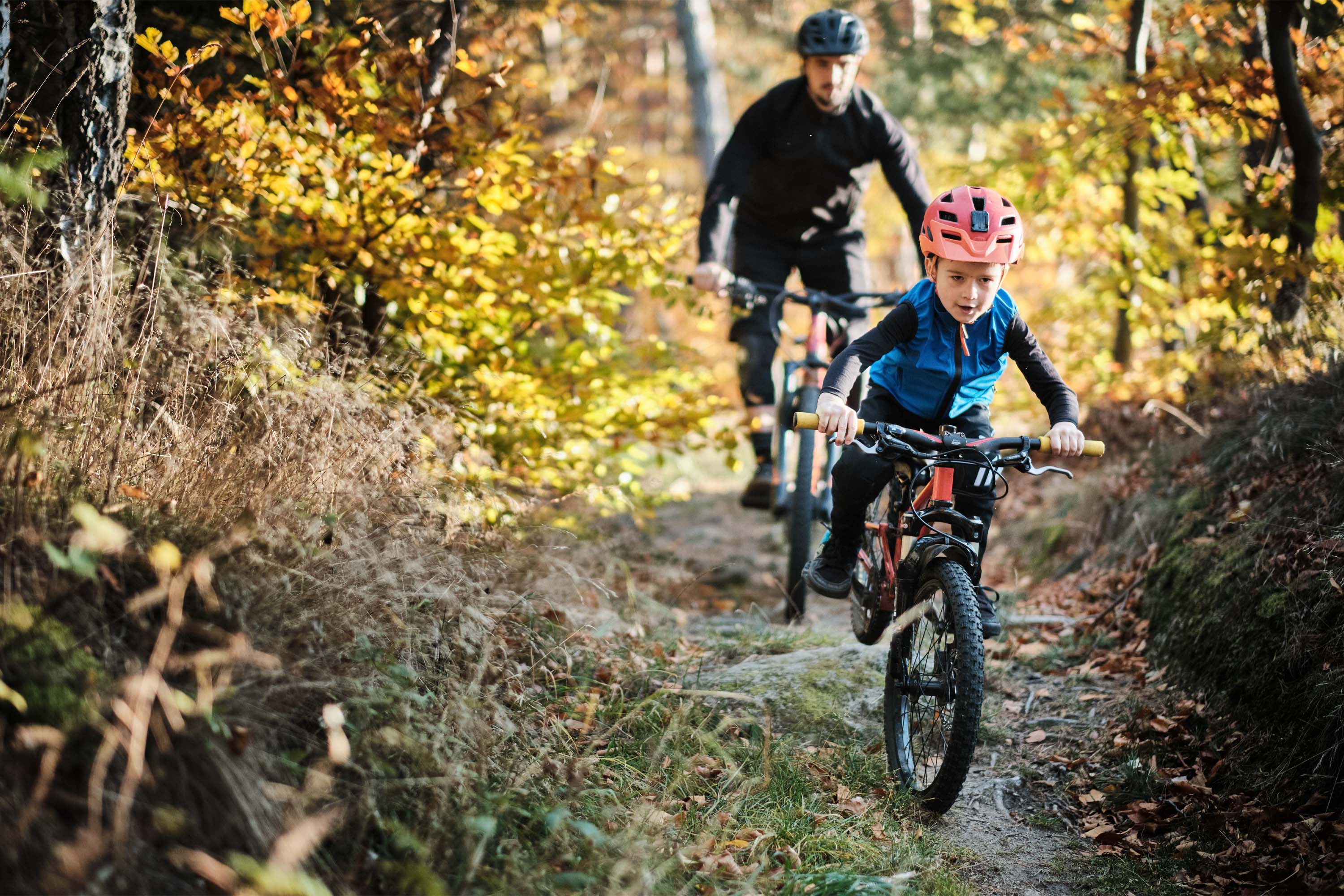 Father and son mountain biking down a trail.